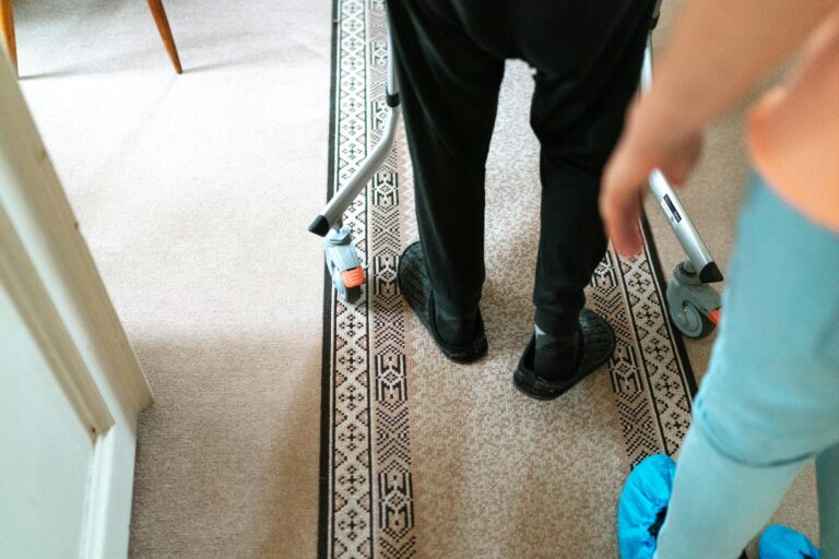 A senior person with a walker assisted by a caregiver in a cozy indoor setting.